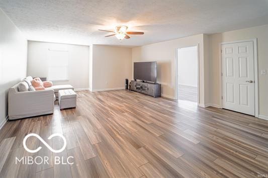 living room featuring wood-type flooring, a textured ceiling, and ceiling fan