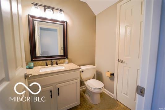 bathroom featuring vanity, toilet, and lofted ceiling