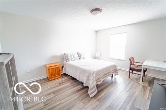 bedroom with a textured ceiling and light hardwood / wood-style flooring