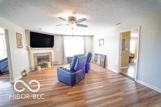 living room with a wealth of natural light, a textured ceiling, and a tile fireplace