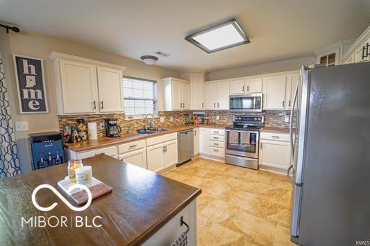 kitchen with decorative backsplash, stainless steel appliances, white cabinetry, and sink