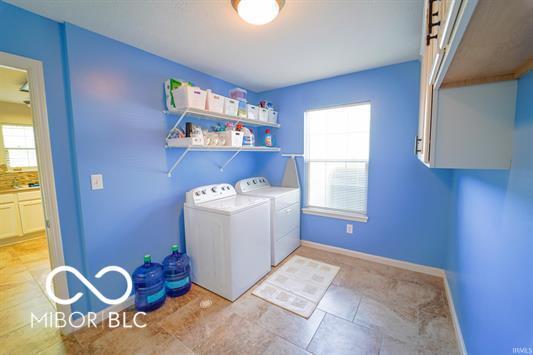 clothes washing area with washer and dryer and cabinets