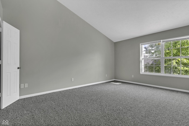 carpeted spare room with vaulted ceiling