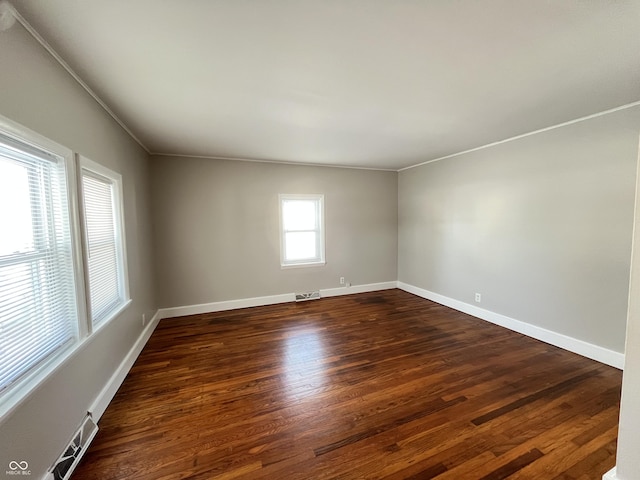 unfurnished room with dark wood finished floors, crown molding, baseboards, and visible vents