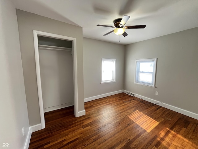 unfurnished bedroom with a closet, baseboards, ceiling fan, and dark wood-style flooring