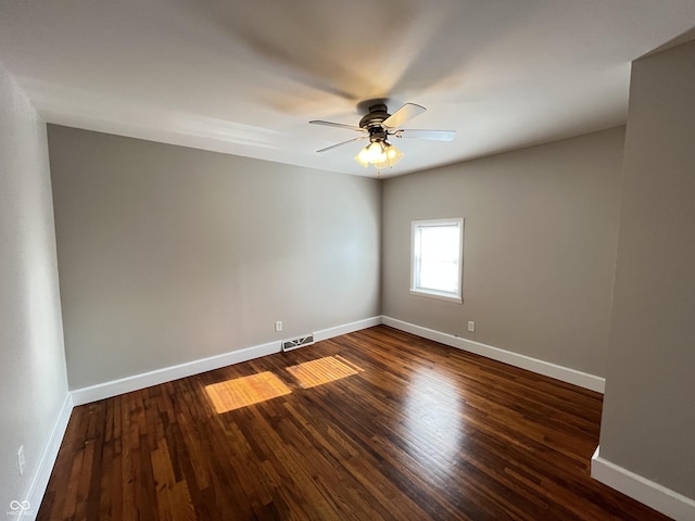 empty room with visible vents, a ceiling fan, dark wood-type flooring, and baseboards