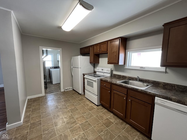 kitchen featuring white appliances, baseboards, washer / dryer, a sink, and dark countertops