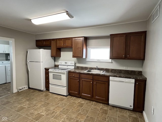 kitchen with dark countertops, visible vents, white appliances, and a sink