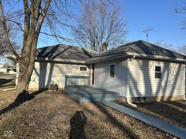 view of side of property with cooling unit, a wooden deck, a chimney, and a shingled roof