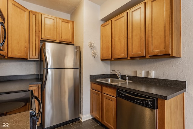 kitchen with sink, stainless steel appliances, and dark tile patterned floors