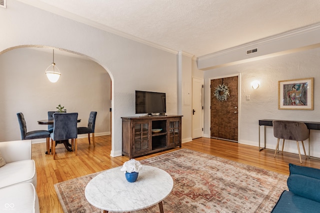 living room featuring wood-type flooring, a textured ceiling, and ornamental molding