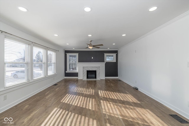 unfurnished living room featuring dark hardwood / wood-style flooring, a premium fireplace, crown molding, and ceiling fan