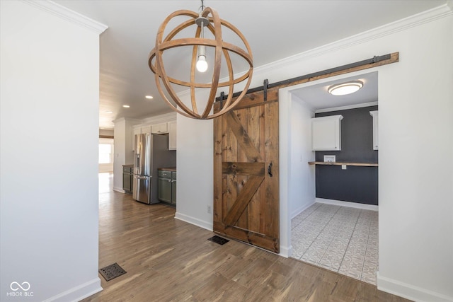 unfurnished dining area with a barn door, dark hardwood / wood-style floors, and ornamental molding