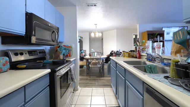 kitchen with sink, a chandelier, decorative light fixtures, light tile patterned flooring, and appliances with stainless steel finishes