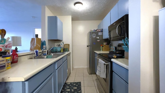 kitchen with blue cabinetry, sink, light tile patterned flooring, and appliances with stainless steel finishes