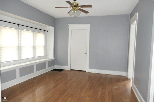 empty room with ceiling fan and dark hardwood / wood-style flooring