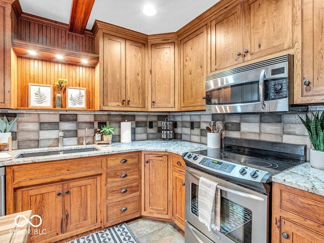 kitchen with light stone countertops, tasteful backsplash, stainless steel appliances, sink, and beam ceiling