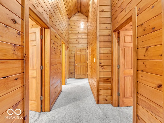 hallway with light carpet, vaulted ceiling, wooden walls, and wood ceiling