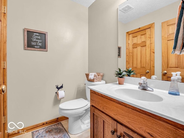 bathroom with toilet, a textured ceiling, vanity, and tile patterned floors