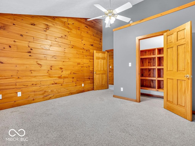 empty room featuring light carpet, lofted ceiling, and wooden walls