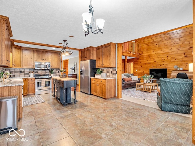 kitchen featuring a center island, hanging light fixtures, stainless steel appliances, a chandelier, and wooden walls