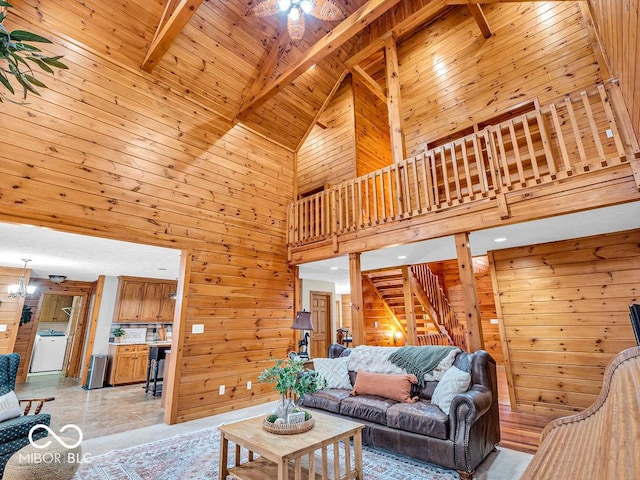 living room featuring beam ceiling, wooden ceiling, high vaulted ceiling, washer / clothes dryer, and wooden walls