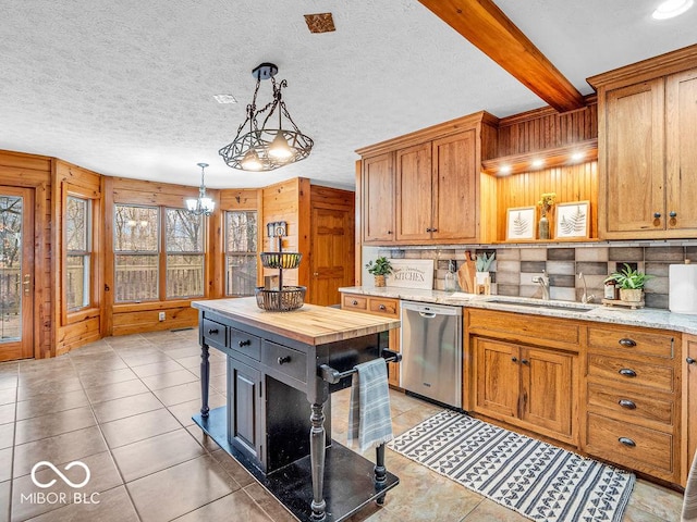 kitchen featuring sink, beam ceiling, pendant lighting, dishwasher, and a center island