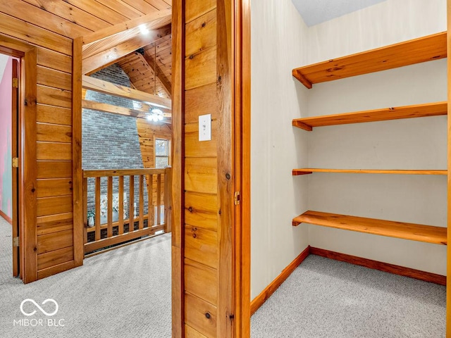 corridor with wood walls, light colored carpet, and wooden ceiling