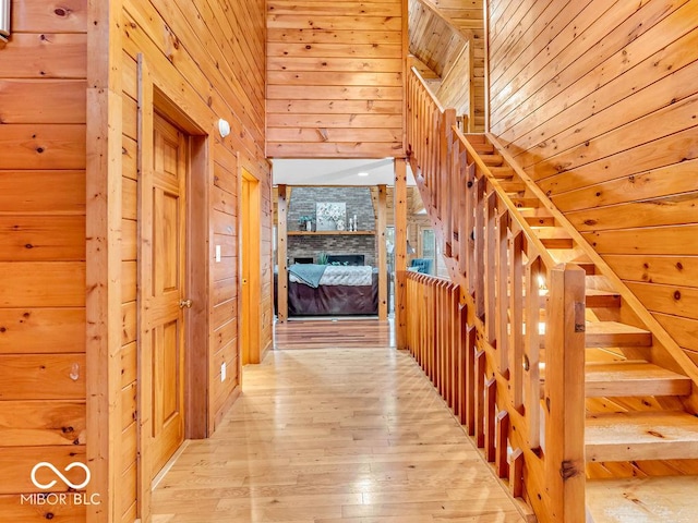 corridor featuring light wood-type flooring and wood walls