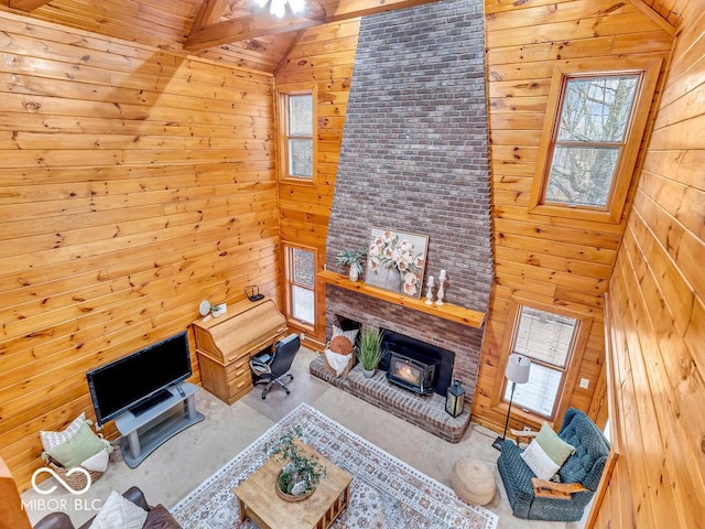 living room featuring wood walls, a wood stove, beam ceiling, and high vaulted ceiling