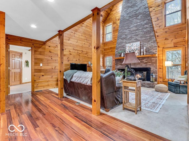 living room featuring a fireplace, hardwood / wood-style flooring, high vaulted ceiling, and wood walls