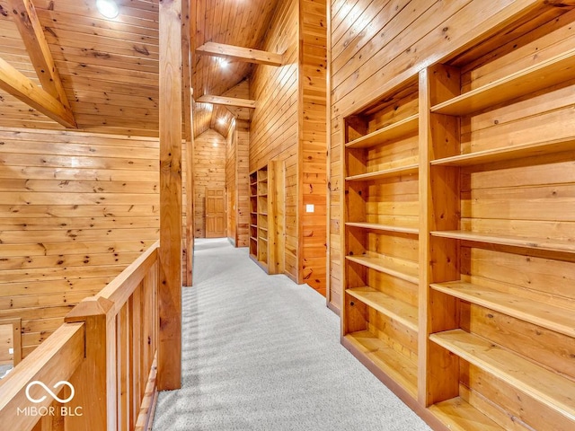 hallway with carpet flooring, wooden walls, wood ceiling, and beam ceiling