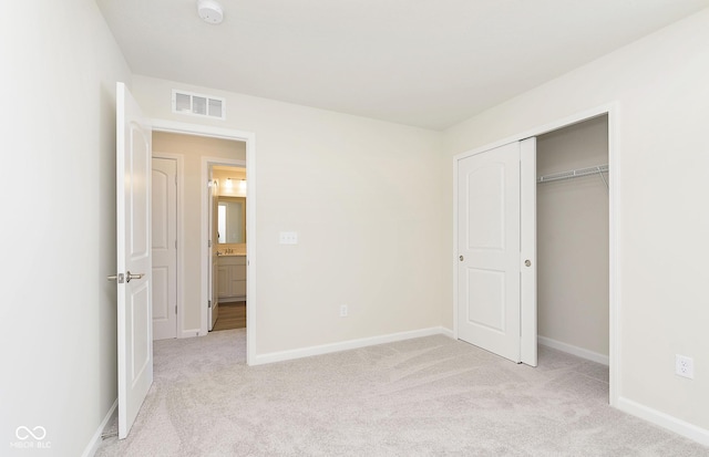 unfurnished bedroom with light carpet and a closet