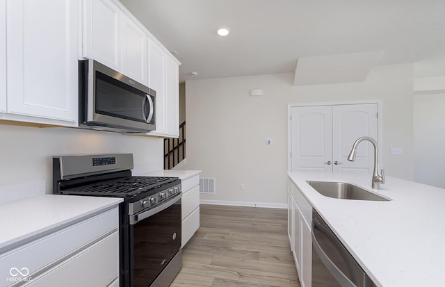 kitchen featuring white cabinetry, appliances with stainless steel finishes, sink, and light hardwood / wood-style floors