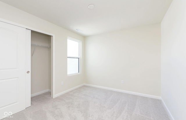 unfurnished bedroom featuring light colored carpet and a closet