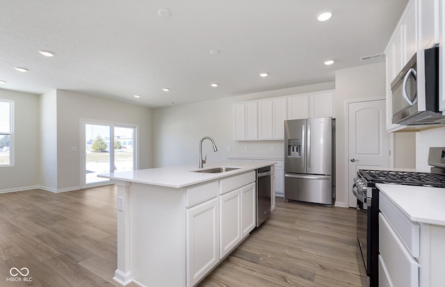 kitchen with an island with sink, appliances with stainless steel finishes, sink, and white cabinets