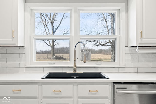 kitchen featuring sink, dishwasher, white cabinetry, plenty of natural light, and tasteful backsplash