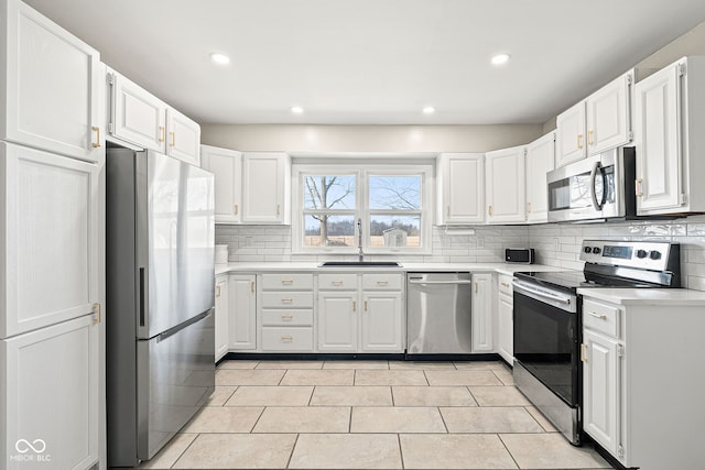 kitchen with white cabinetry, appliances with stainless steel finishes, sink, and backsplash