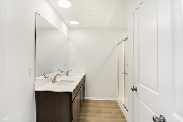 bathroom with hardwood / wood-style floors, vanity, and a shower with door