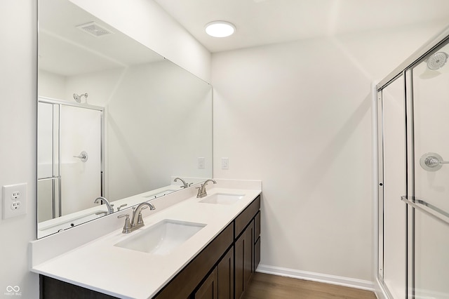 bathroom with hardwood / wood-style flooring, vanity, and walk in shower