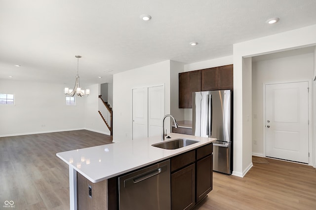 kitchen with sink, stainless steel appliances, a chandelier, decorative light fixtures, and a kitchen island with sink