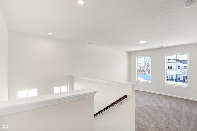 hallway featuring light colored carpet and a textured ceiling