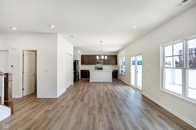 kitchen with a center island, wood-type flooring, decorative light fixtures, dark brown cabinets, and appliances with stainless steel finishes