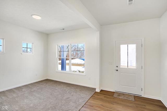 entryway featuring beam ceiling, a healthy amount of sunlight, and light wood-type flooring