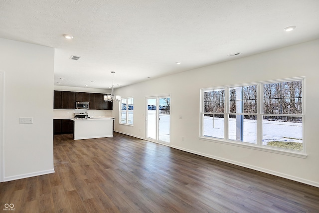 kitchen featuring stainless steel appliances, dark hardwood / wood-style floors, an island with sink, decorative light fixtures, and dark brown cabinets