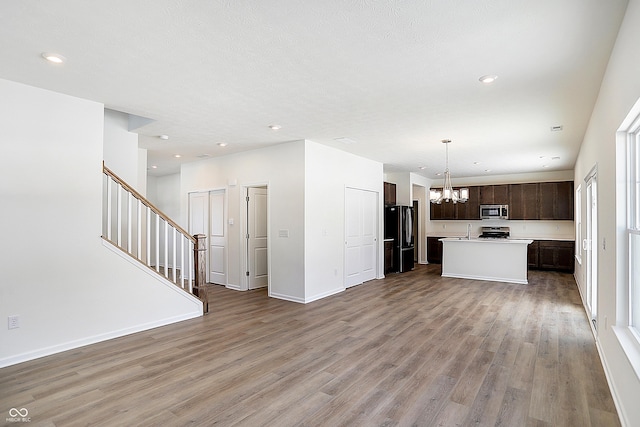 unfurnished living room featuring sink, wood-type flooring, and an inviting chandelier