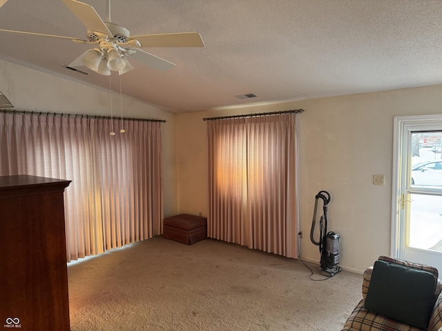 carpeted spare room featuring ceiling fan, lofted ceiling, and a textured ceiling