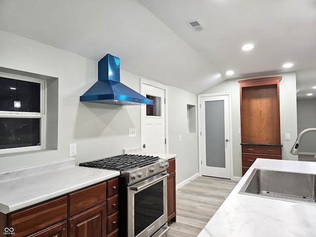 kitchen with exhaust hood, vaulted ceiling, light hardwood / wood-style floors, sink, and stainless steel range with gas stovetop