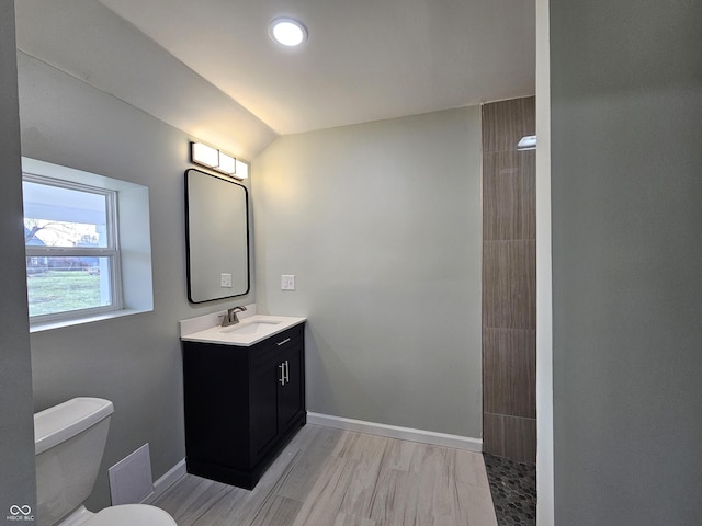 bathroom featuring lofted ceiling, vanity, a shower, and toilet