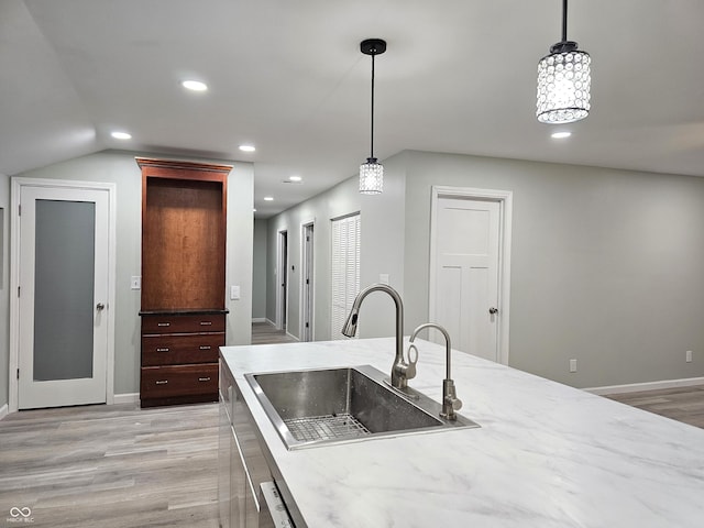 kitchen featuring hanging light fixtures, sink, and light hardwood / wood-style flooring